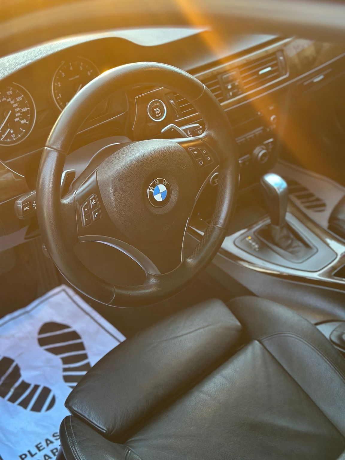 Driver's seat and steering wheel of a BMW with a protective floor mat in place
